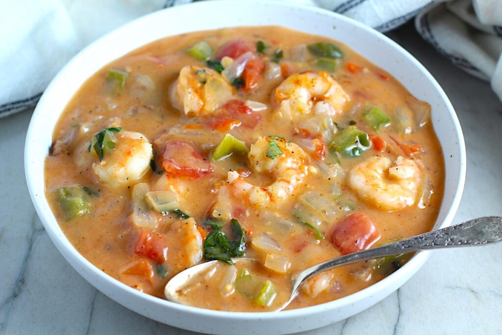 Coconut Shrimp Stew or Moqueca de Camarão, in a bowl with a spoon. It's a delicious traditional dish in Brazil. It's a creamy stew with coconut milk and vegetables.