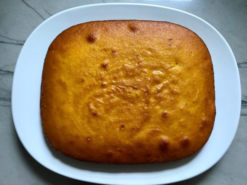 Cooked Brazilian Carrot Cake without the topping on, sitting on a platter.