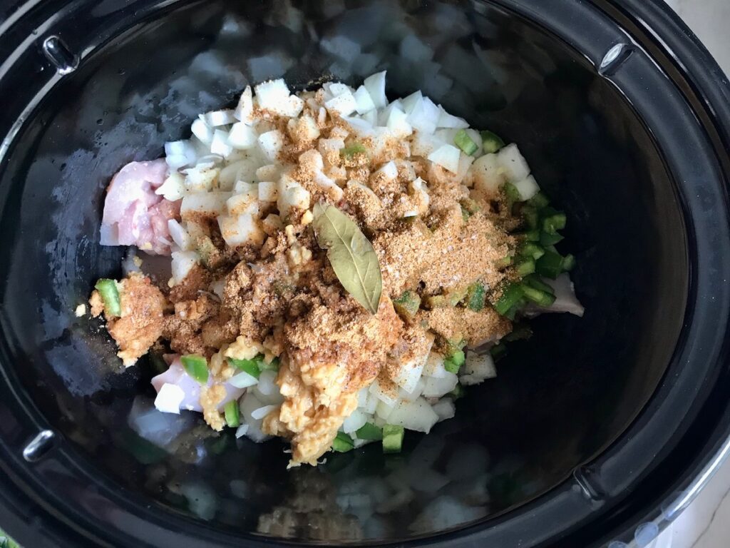 Cut chicken thighs, onions, jalapeno, seasonings, and bay leaf in slow cooker for Brazilian Coconut Chicken stew.