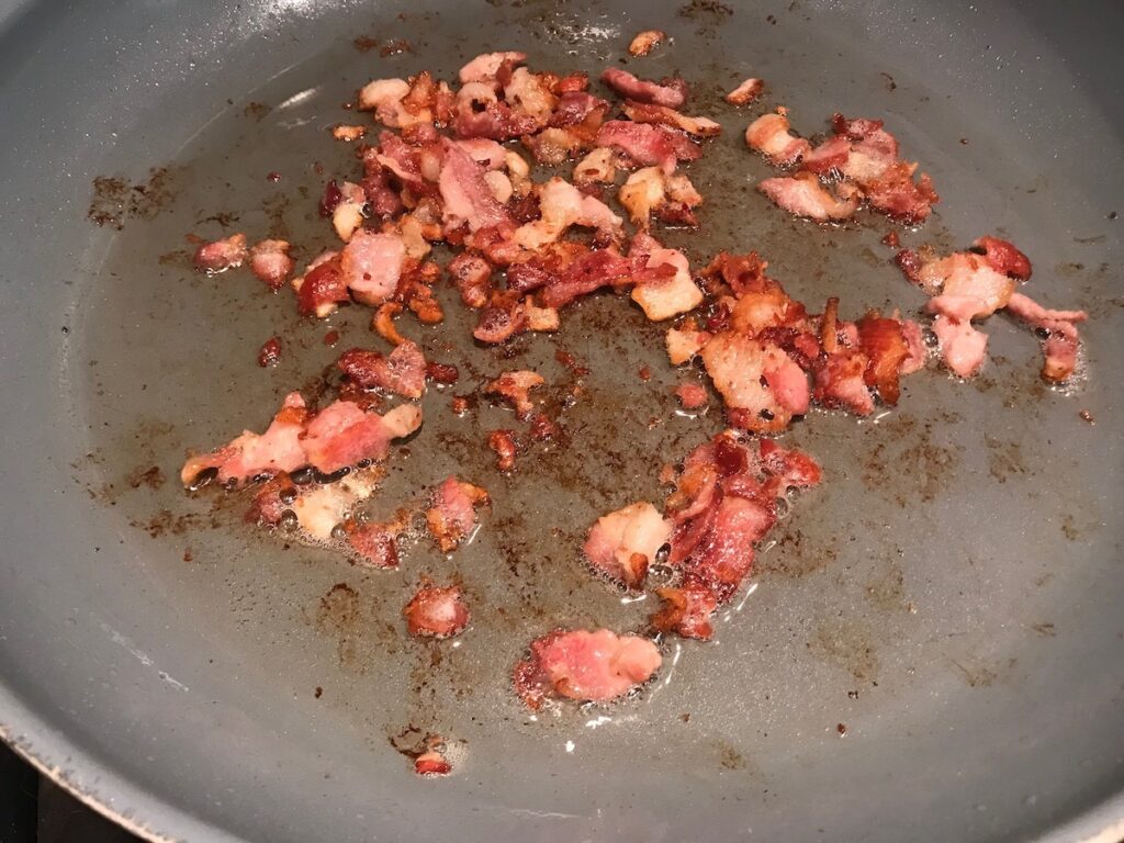 Crispy diced bacon cooked in a pan with fat rendered for Kale with bacon recipe.