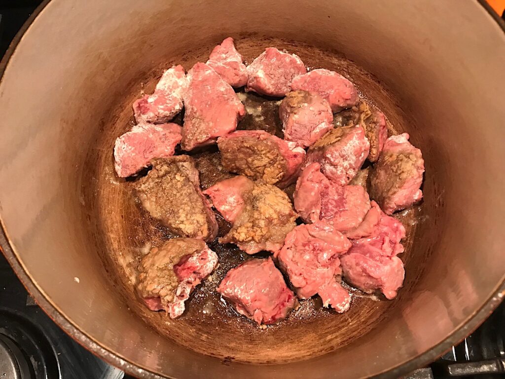 Floured beef cubes cooking in a dutch oven for Brazilian Beef Stew Stove Top recipe.