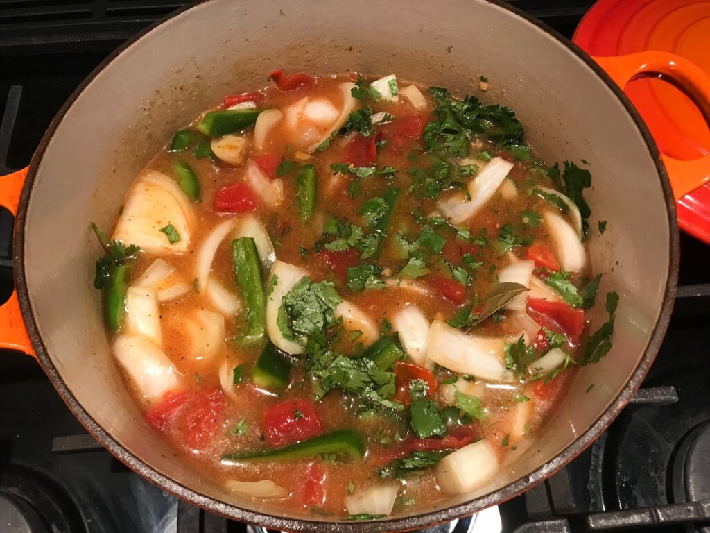 All ingredients (onions, green pepper, cilantro, diced tomatoes, broth) cooking in a dutch oven for Brazilian Beef Stew Stove Top recipe.