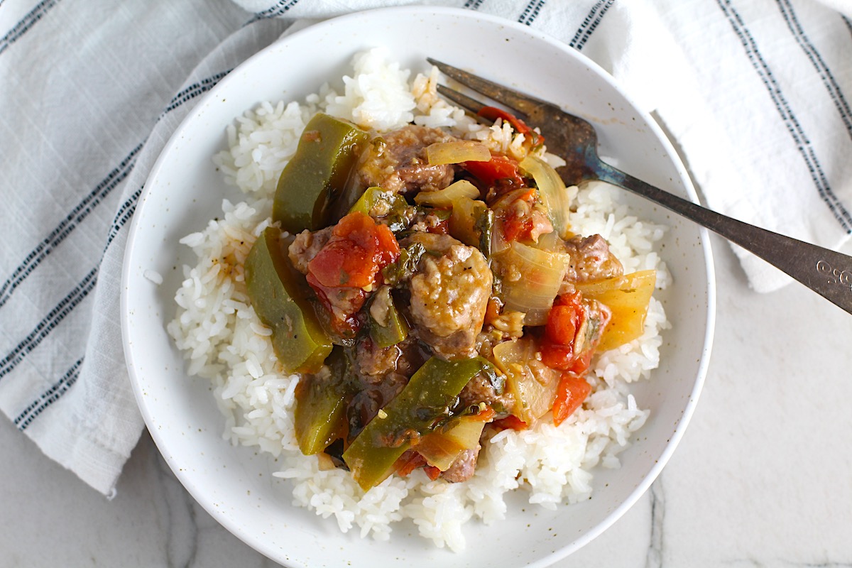 Cooked Brazilian Beef Stew Stove Top recipe over rice in bowl with fork in it on counter. It's a savory, succulent and hearty dish that you can make anytime!