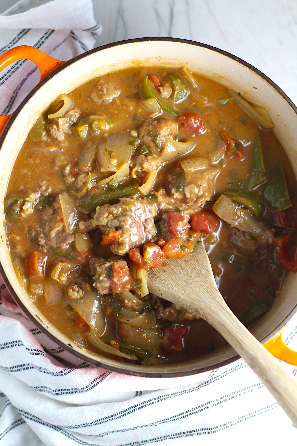 Cooked Brazilian Beef Stew Stove Top recipe in a pot with wooden spoon in it on counter with dish towel. It's a savory, succulent and hearty dish that you can make anytime!