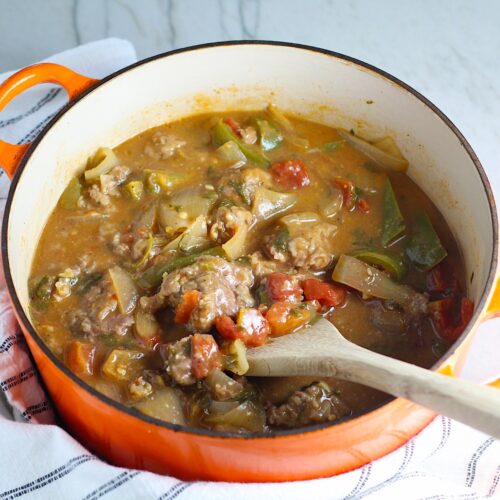Cooked Brazilian Beef Stew Stove Top recipe in a pot with wooden spoon in it on counter with dish towel. It's a savory, succulent and hearty dish that you can make anytime!