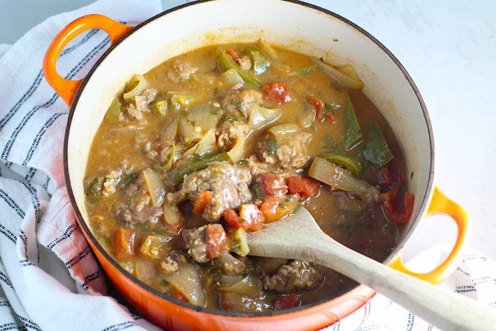 Cooked Brazilian Beef Stew Stove Top recipe in a pot with wooden spoon in it on counter with dish towel. It's a savory, succulent and hearty dish that you can make anytime!