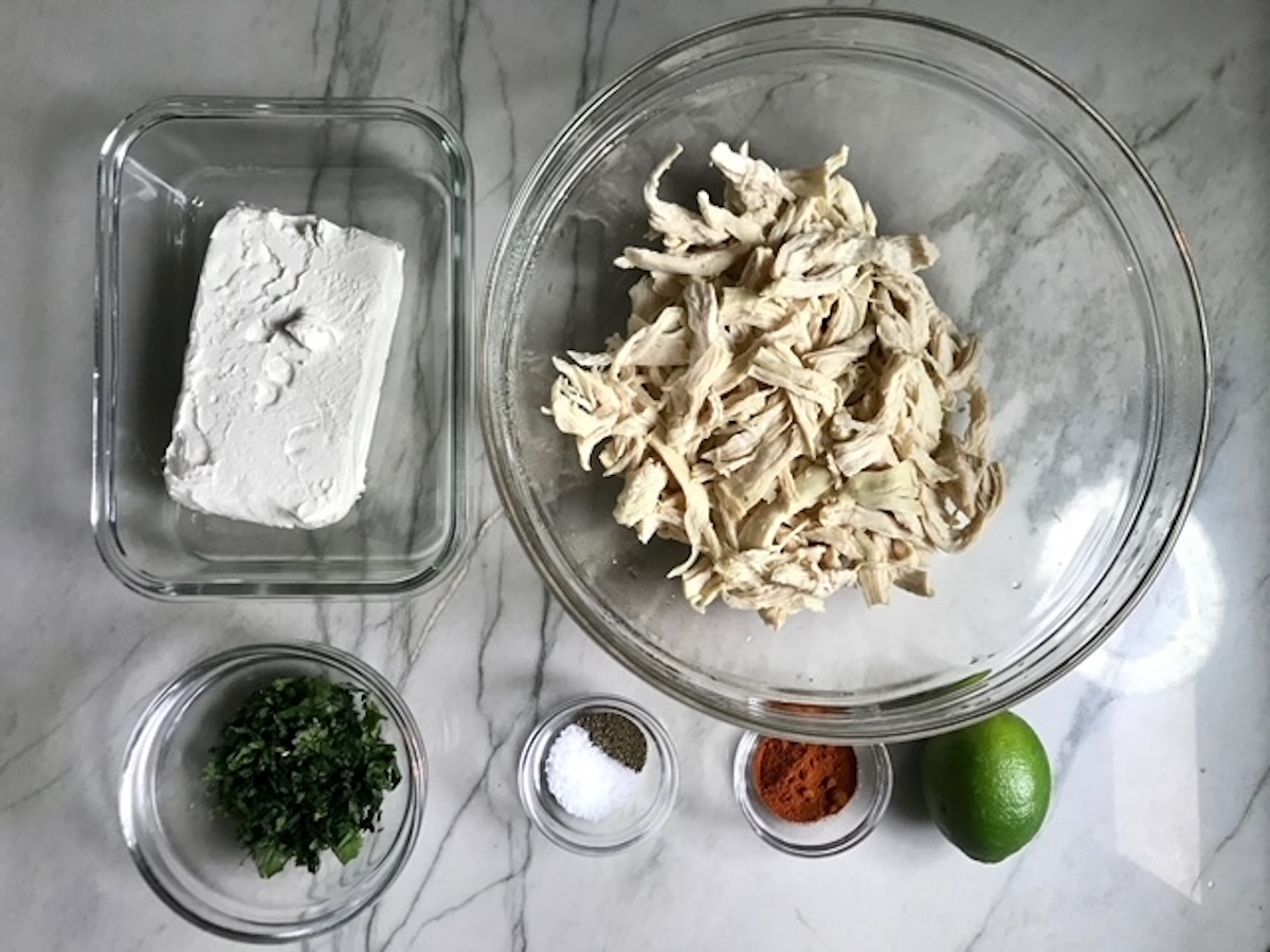 Ingredients prepped in bowls on counter (shredded chicken, cream cheese, cilantro, salt, pepper, paprika, lime) for Coxinha Chicken Croquettes.