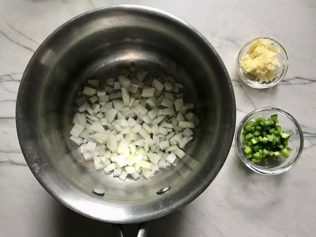 Vegetables prepped in bowls on counter (diced onion, minced garlic, diced jalapeno) for Coxinha Chicken Croquettes.