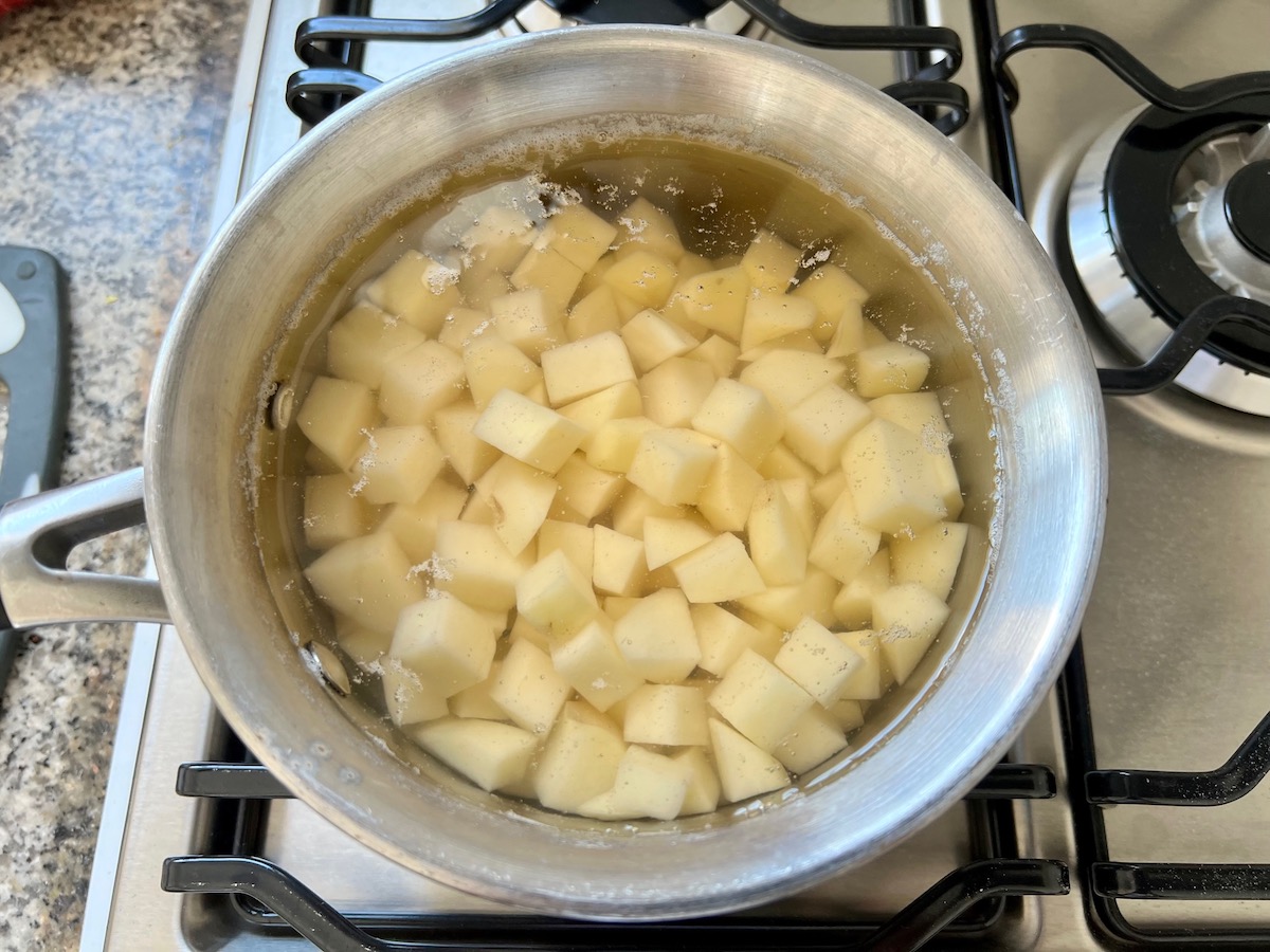 Diced potatoes in water in a pot on the stove for the Brazilian Potato Salad.