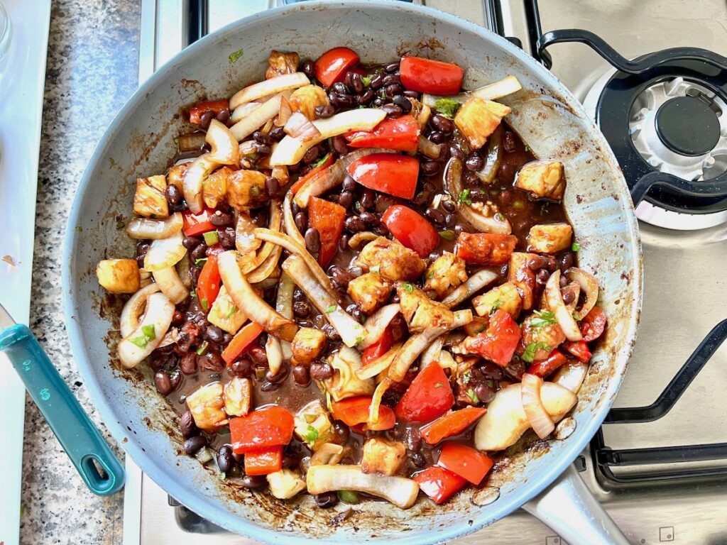 Sauce, black beans and cilantro added to Marinated Chicken Stir Fry recipe with red peppers, pineapple, and onions.