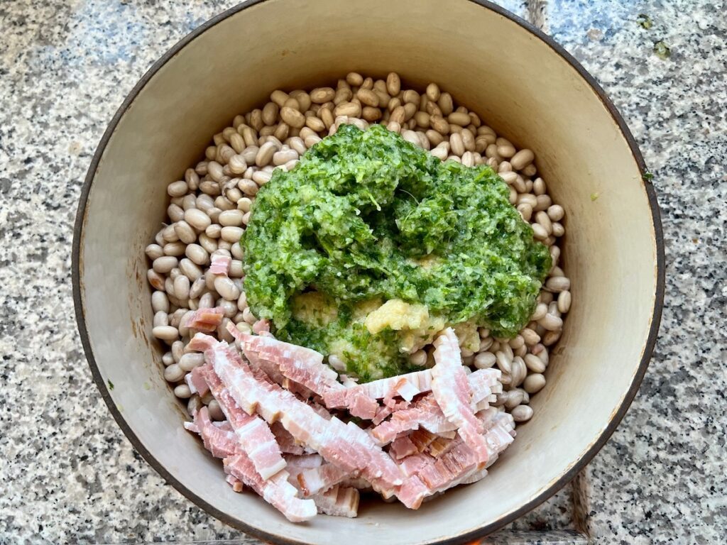 Carioca (pinto) beans in a dutch oven pot with the sliced bacon, the puréed mixture of onions, garlic, and cilantro for this Carioca Beans recipe.
