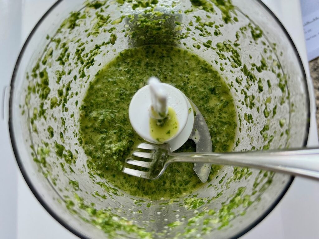 Brazilian Cilantro Chimichurri recipe blended in a food processor with a fork scooping some up.