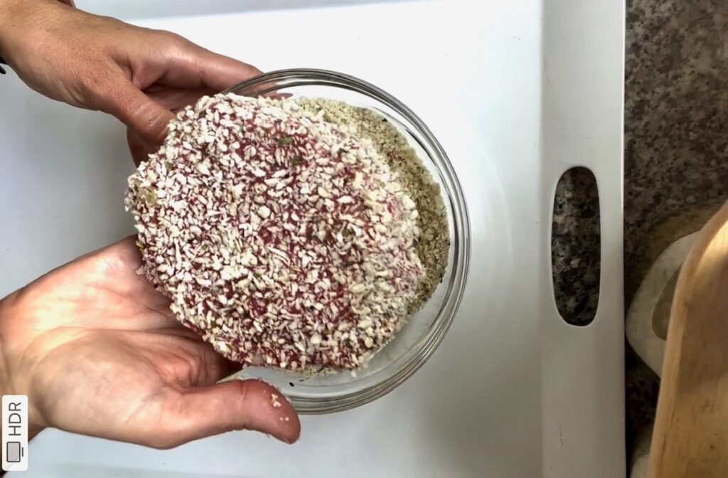 Hands holding a polpettone beef patty that has been coated in breadcrumbs.