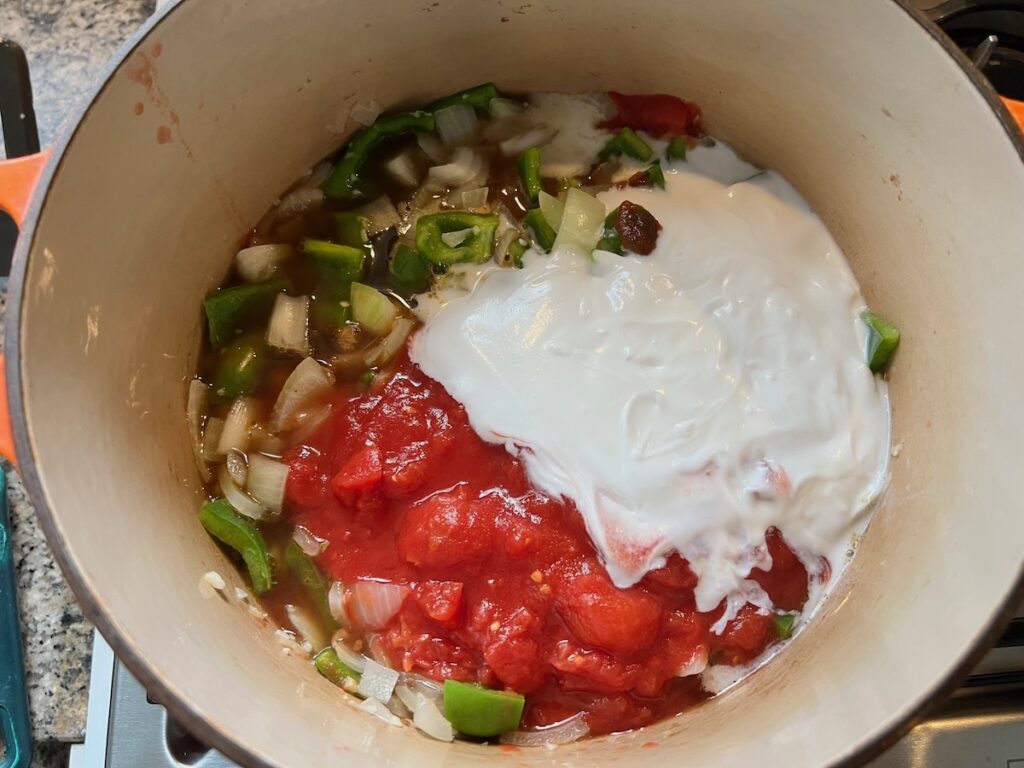 Diced tomatoes, coconut milk, green peppers, onions in a pot for Moqueca de Ovos.