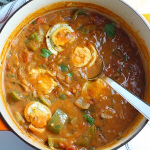 Moqueca de Ovos in a dutch oven pot with sliced hard boiled eggs sitting on top. This is a vegetarian version of a traditional stew in Brazil, where hard boiled eggs replace the seafood.
