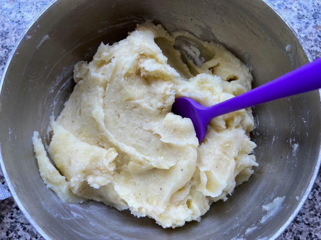 Mashed potatoes in pot with spatula for Dutch oven Shepherd's Pie.