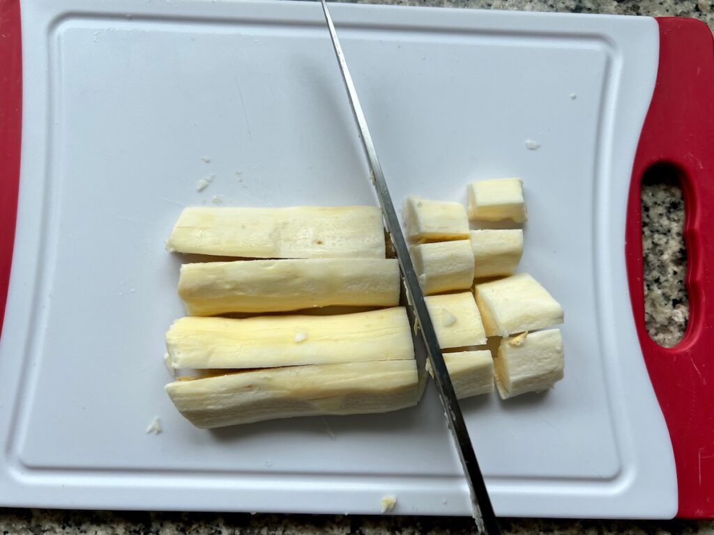 Knife cutting peeled yucca root for Vaca Atolada Brazilian beef stew.