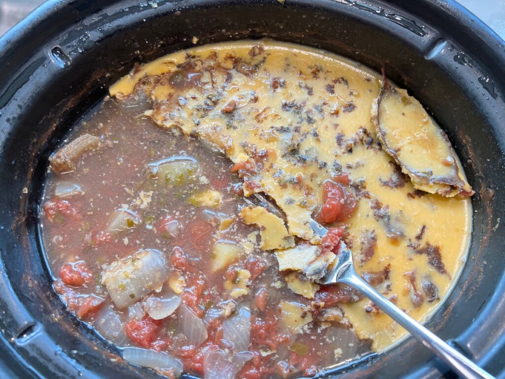 Fork scraping up the congealed fat from the top of the cooled Vaca Atolada Beef Stew.