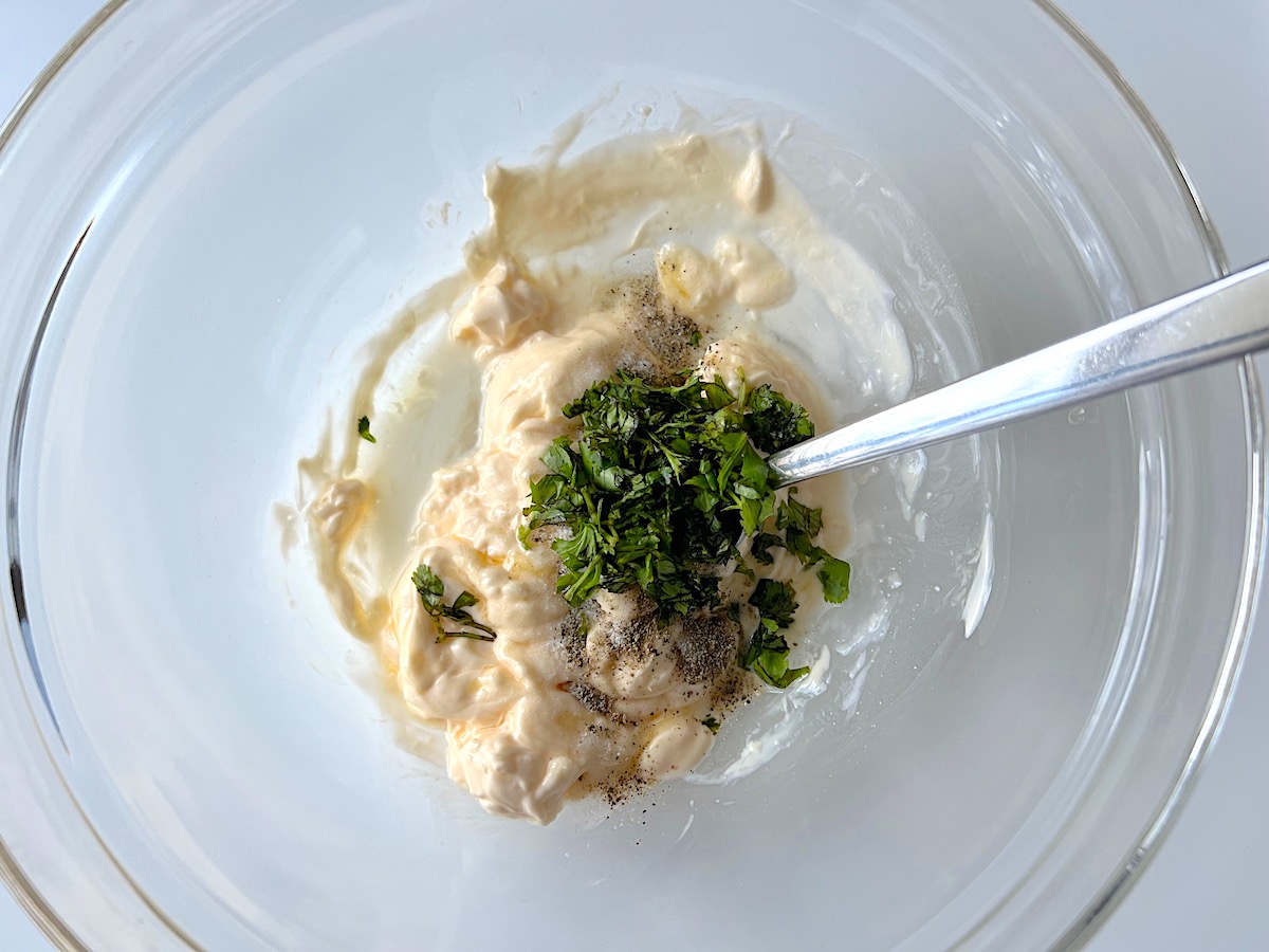 Mayonnaise, honey, vinegar, salt, ground pepper, and cilantro in bowl for Brazilian Chicken Salad.