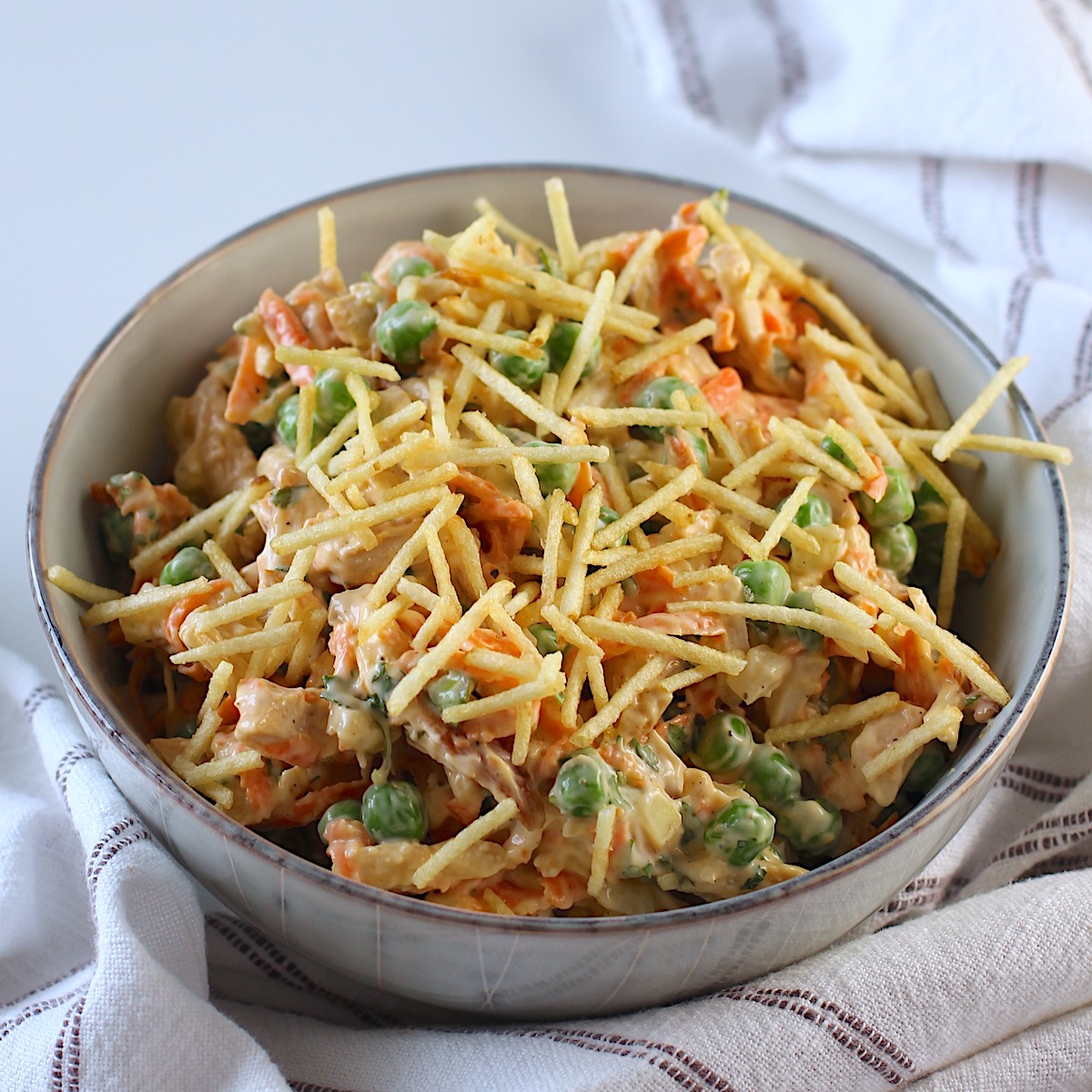 Brazilian Chicken Salad in a bowl with crispy potato sticks on top.