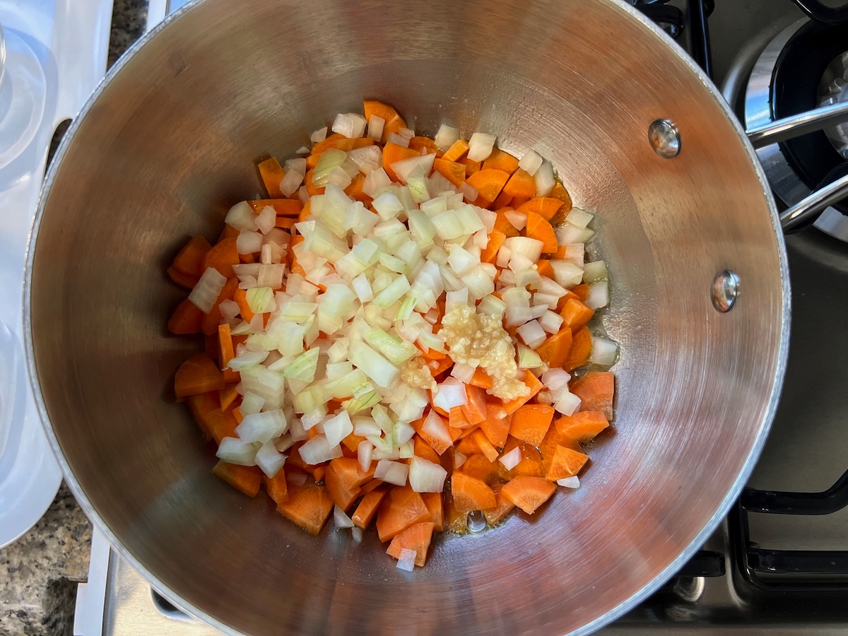 Diced carrots, onions, and minced garlic in a pot cooking for Carrot Sauce.