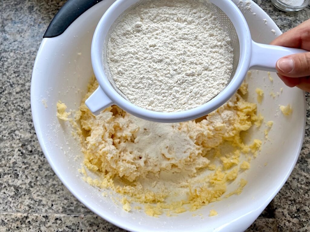 Flour being sifted into butter and sugar mixture for Brigadeiro Brazilian Cake.