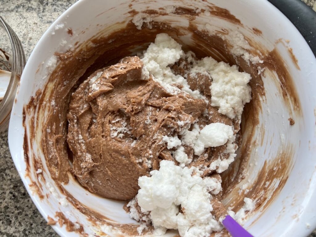 Whipped egg whites being folded into the cake batter for Brigadeiro Brazilian Cake.