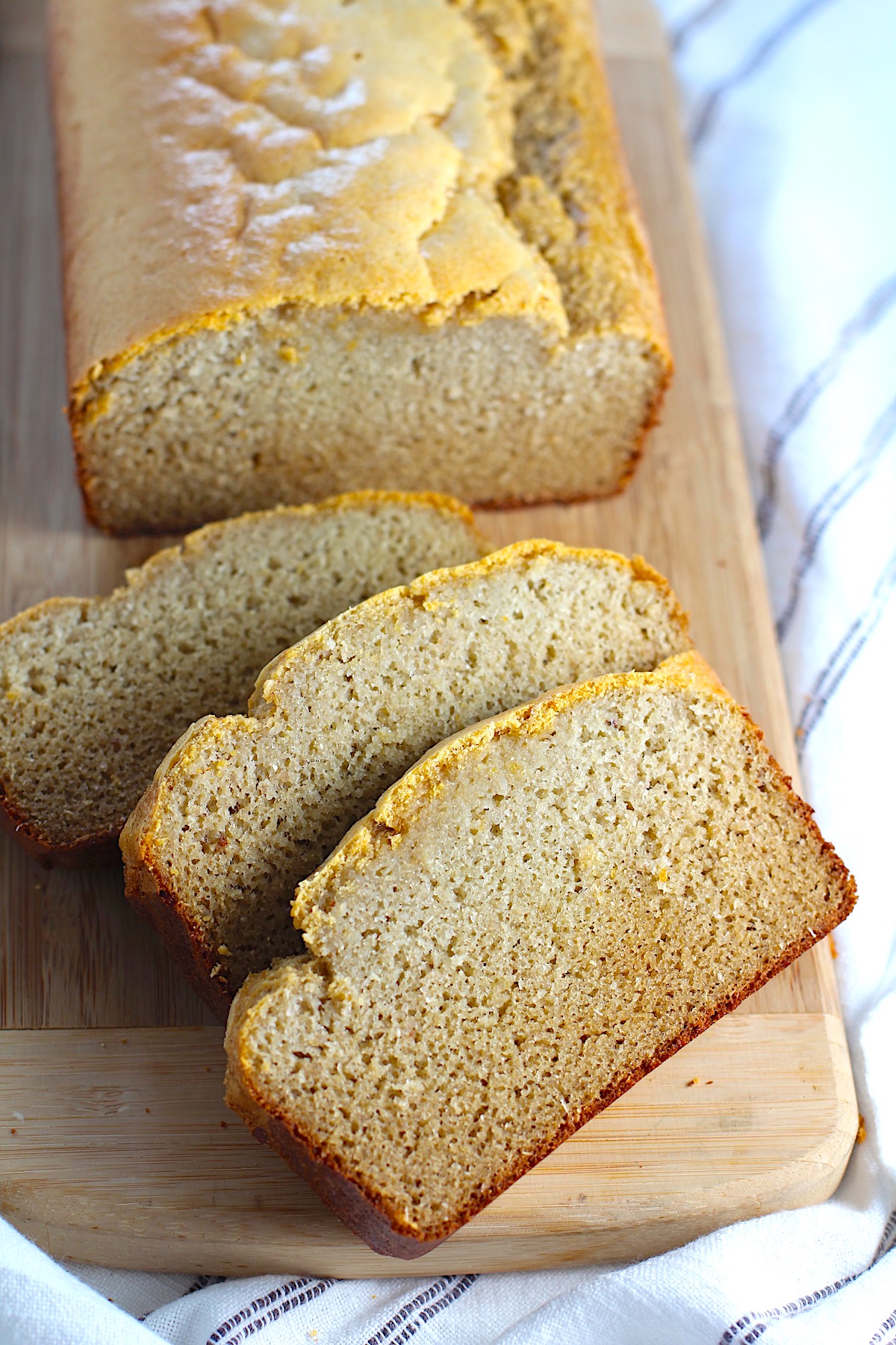 Cassava Bread loaf on a wood cutting board with 3 slices cut and fanned out.