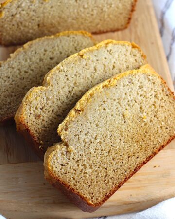 Cassava Bread loaf on a wood cutting board with 3 slices cut and fanned out.