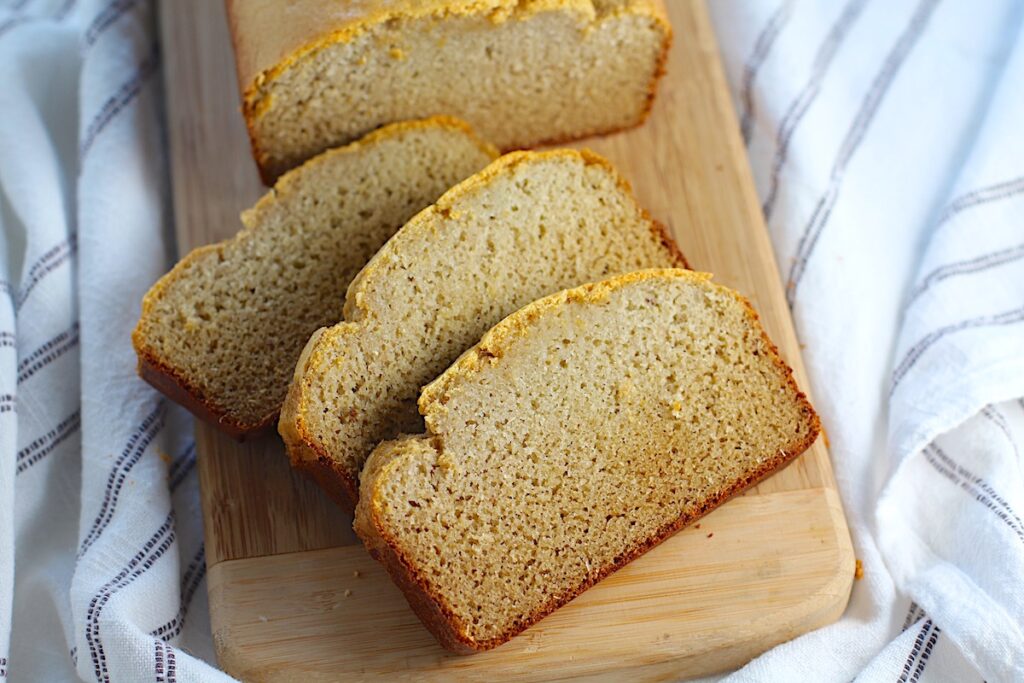 Cassava Bread loaf on a wood cutting board with 3 slices cut and fanned out.