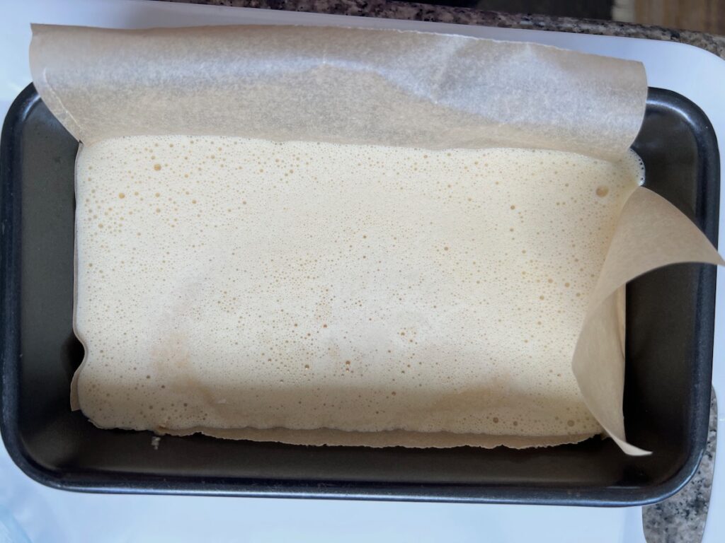 Cassava bread batter in a parchment lined loaf pan before baking.