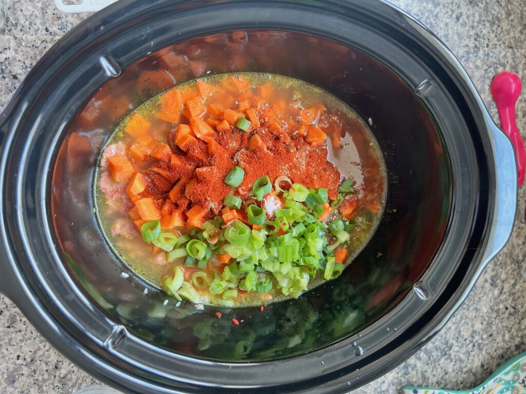 Crockpot insert on counter with raw ground port and uncooked rice added for Ground Pork Slow Cooker Casserole.