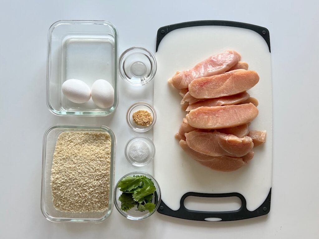 Ingredients prepped and measured out in bowls and chicken cut on cutting board for Panko Chicken recipe.