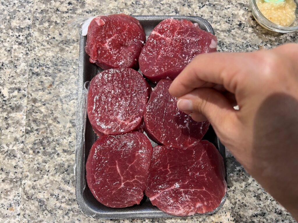 Hand sprinkling coarse salt over Beef with Garlic Sauce.