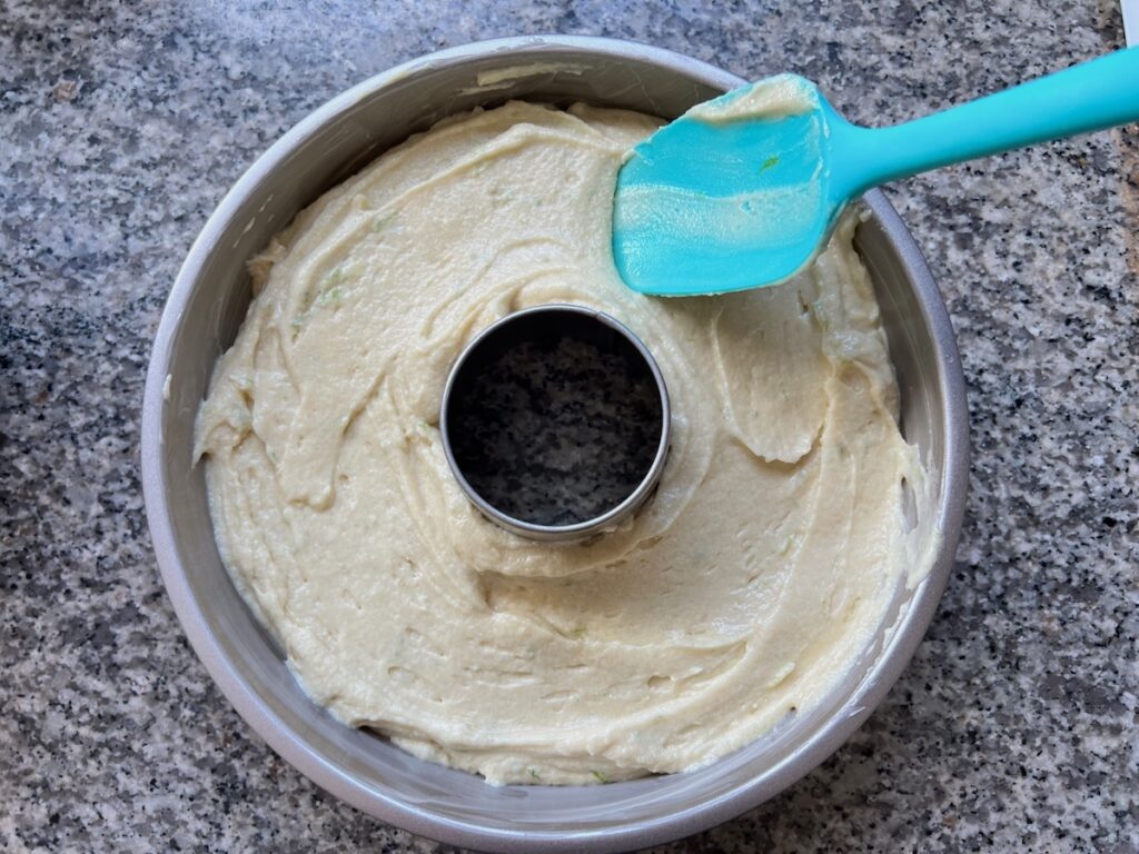 Spatula spreading the batter evenly into a bundt pan or tube pan before baking for Cake with Lime recipe.