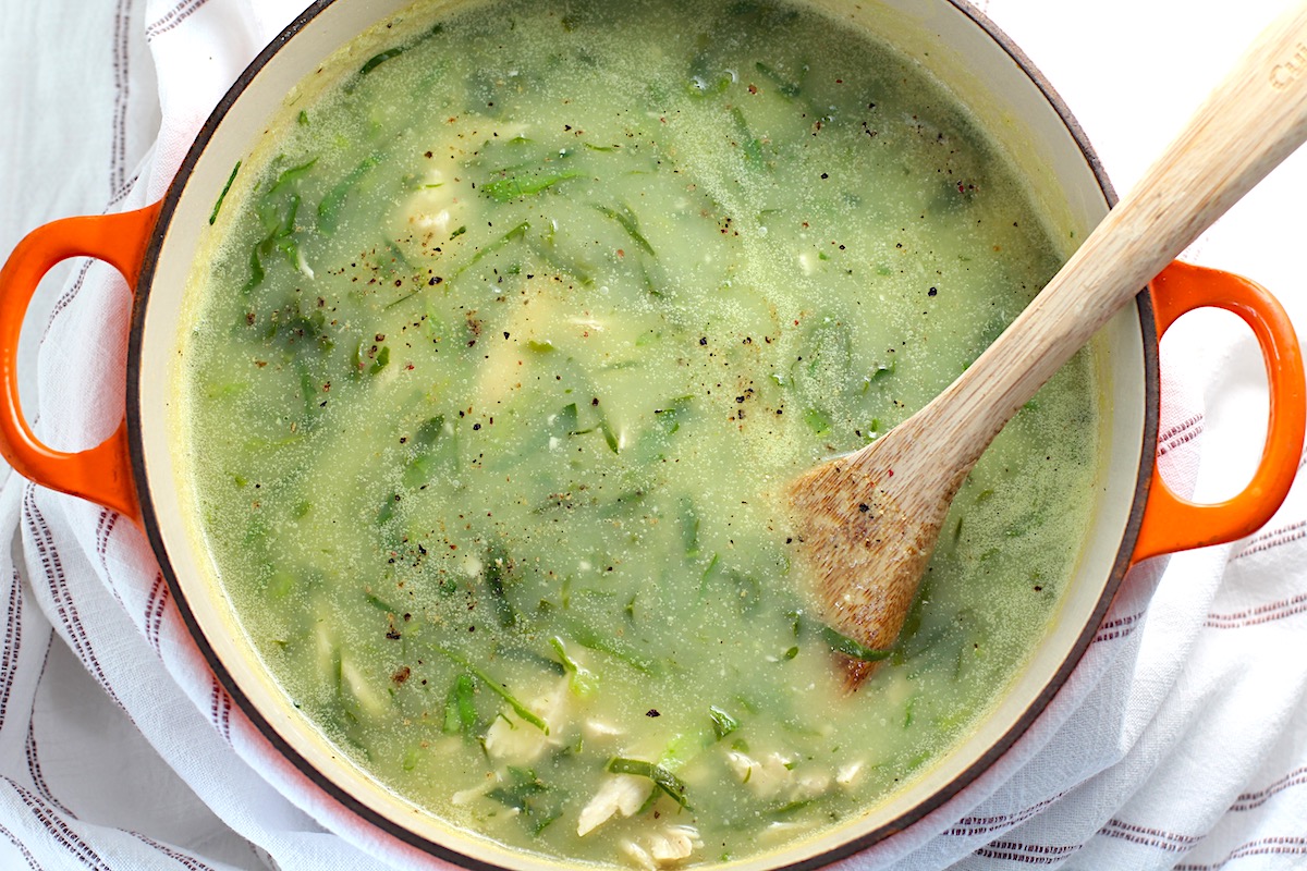 Chicken Kale Soup thickened with pureed potatoes (Caldo Verde com Frango) in a pot with wood spoon on table with towel.