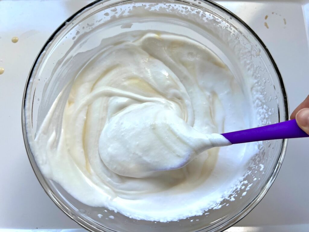 Spatula folding in the condensed milk into the whipped coconut milk cream for Coconut Ice Cream Recipe without Cream.