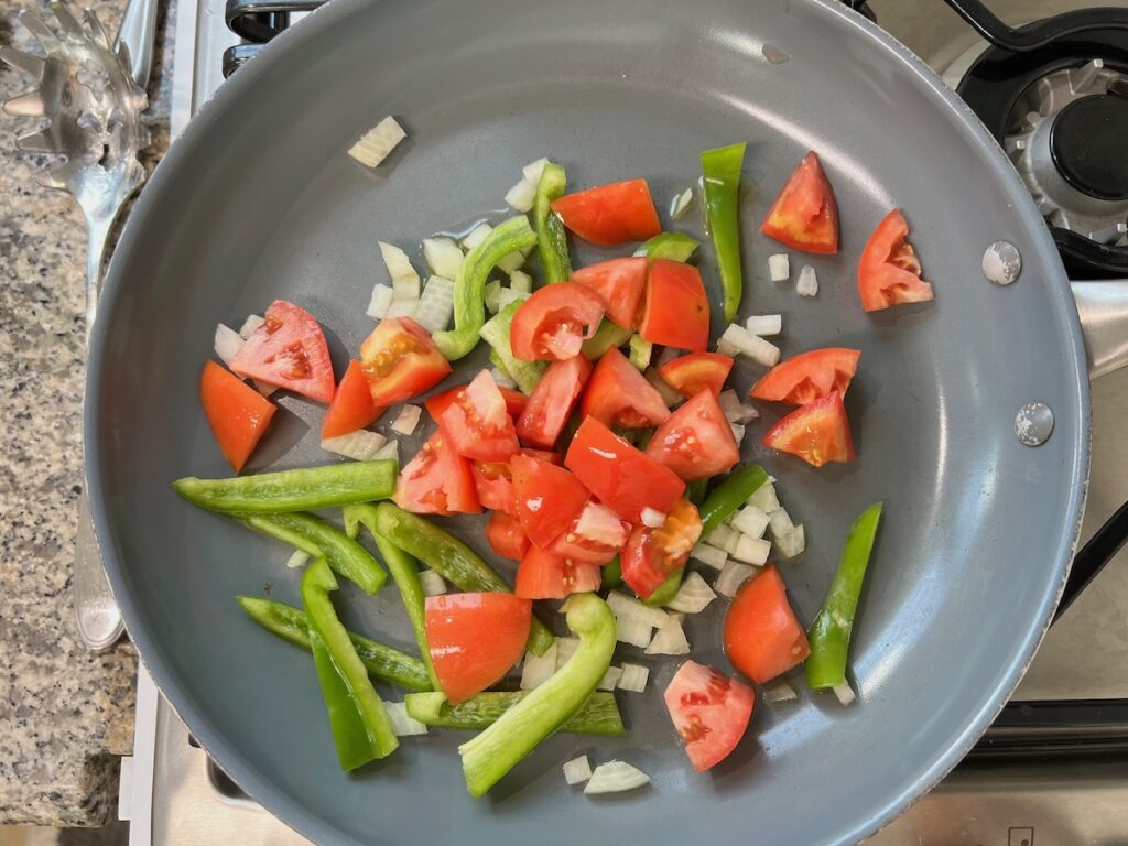 Onions, green pepper, and tomatoes in pan cooking for Coconut Milk Pasta Sauce.