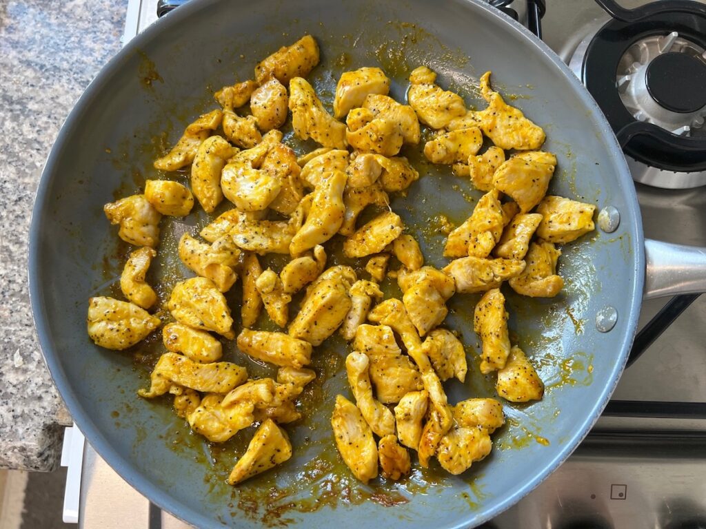 Marinated chicken pieces cooked in a skillet starting to cook on stove for Honey Lemon Pepper Chicken recipe.