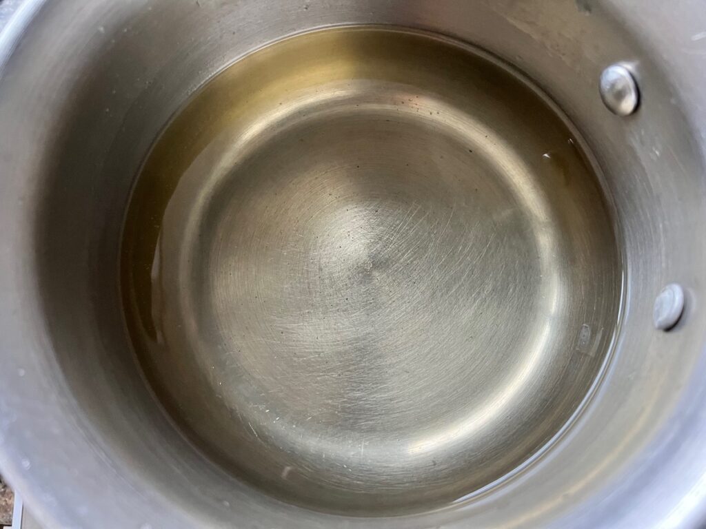 Granulated sugar dissolved into water in a pot on the stove for simple syrup for How to make Strawberry Acai Refresher.