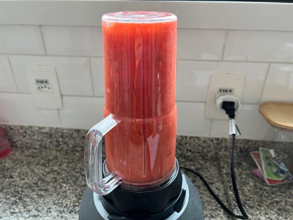 Strawberries and tea blending in a smoothie blender for How to make Strawberry Acai Refresher.