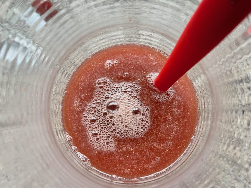 Acai mixture being poured into strawberry mixture for the recipe How to make strawberry acai refresher.