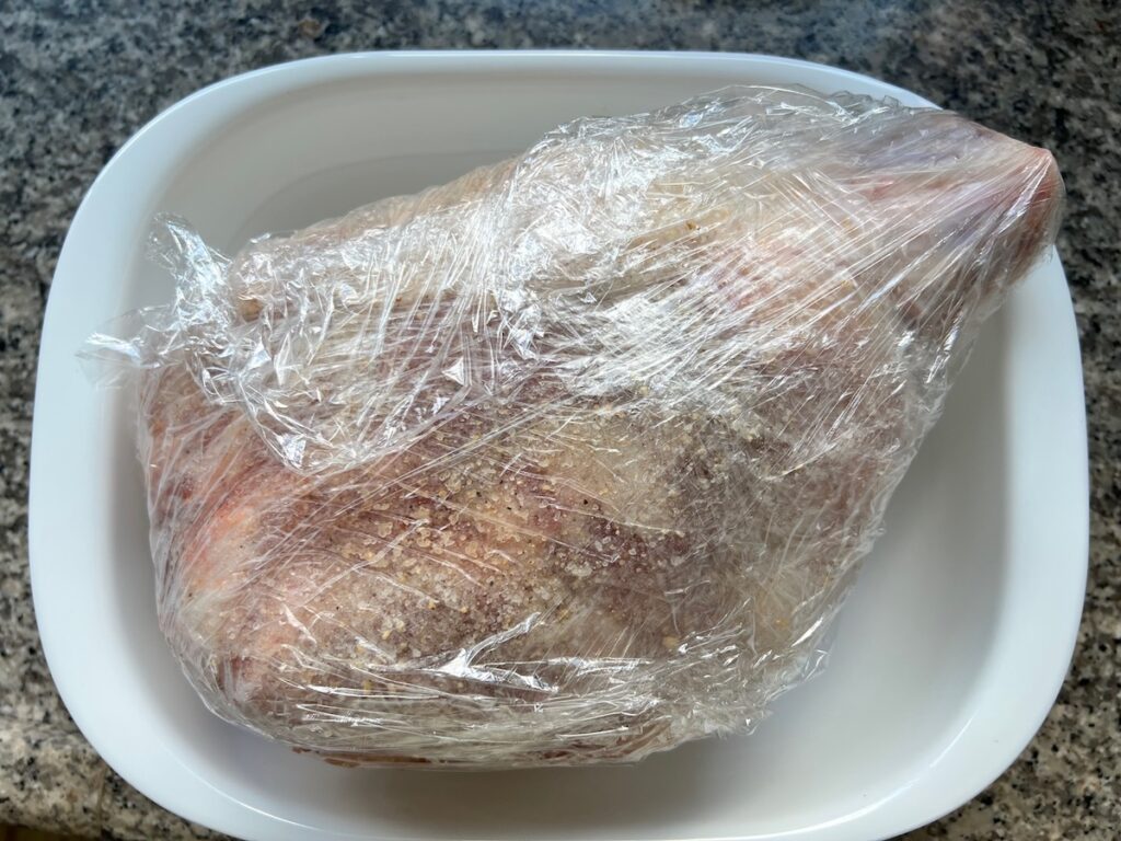 Pork shoulder wrapped tightly in plastic wrap after adding the pork shoulder brine recipe.
