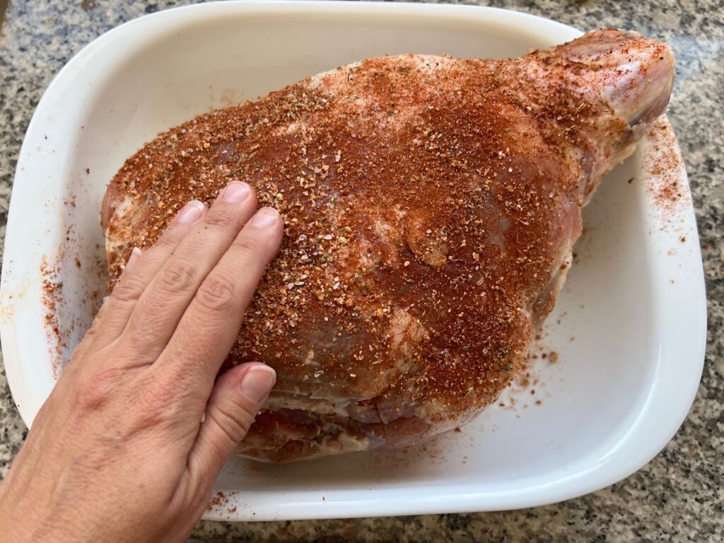 Hand rubbing in the seasoning into the raw pork shoulder after it was already brined and rinsed and dried.