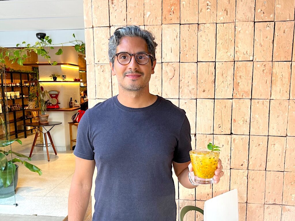 Chef Ricardo Cubas holding a Passion Fruit Caipirinha in front of his store and restaurant, Casa Conceição Empório e Rotisserie in São Paulo, Brazil.