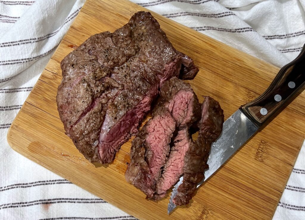 Flank Steak being sliced on cutting board to show Churrasco in the air fryer.