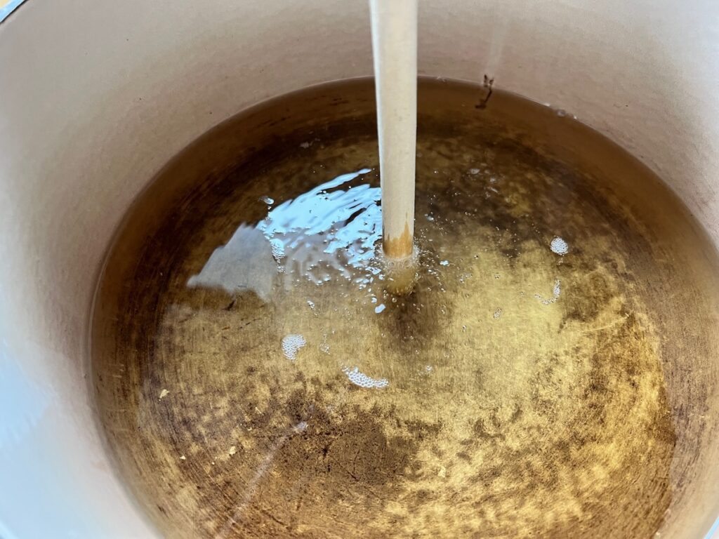 Wooden spoon handle in hot oil checking to see if it's hot and the oil is bubbling around the wood for Brazilian French Toast with Condensed Milk.