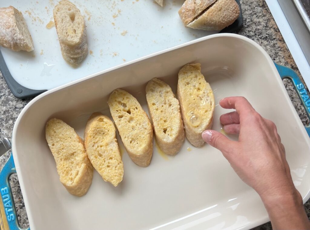 Bread slices soaked and coated in egg placed into a large shallow dish before being friedfor Brazilian French Toast with Condensed Milk.