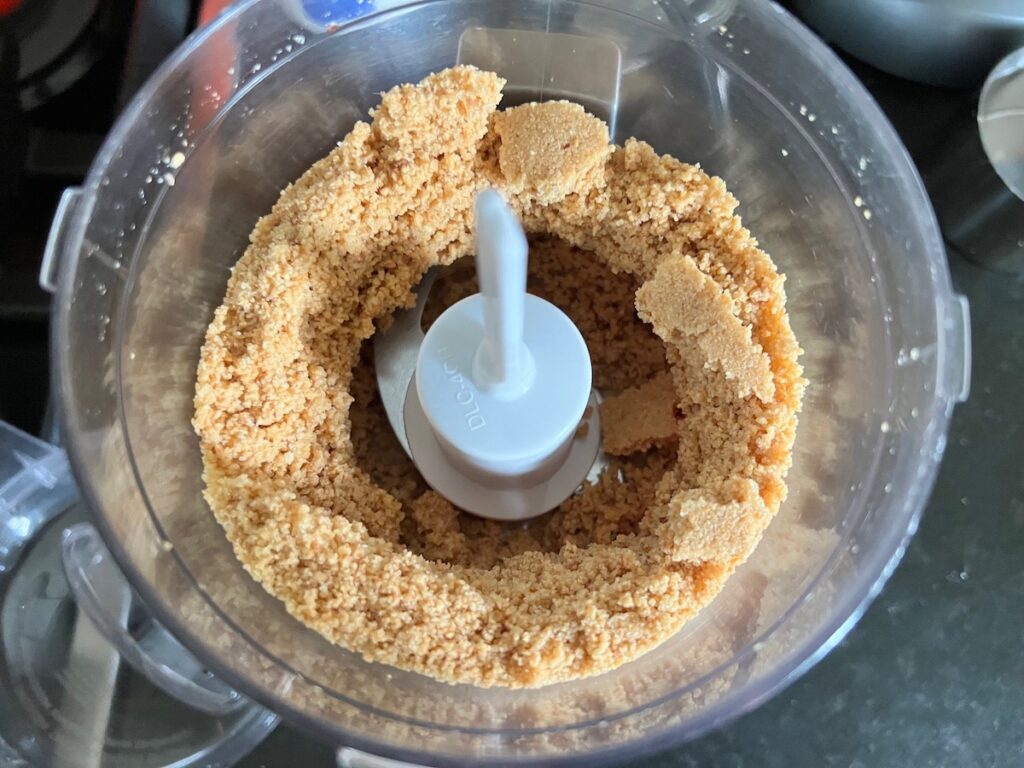 Roasted peanuts, granulated sugar, and salt in a food processor being blending for Brazilian Peanut Candy recipe (Pacoca).
