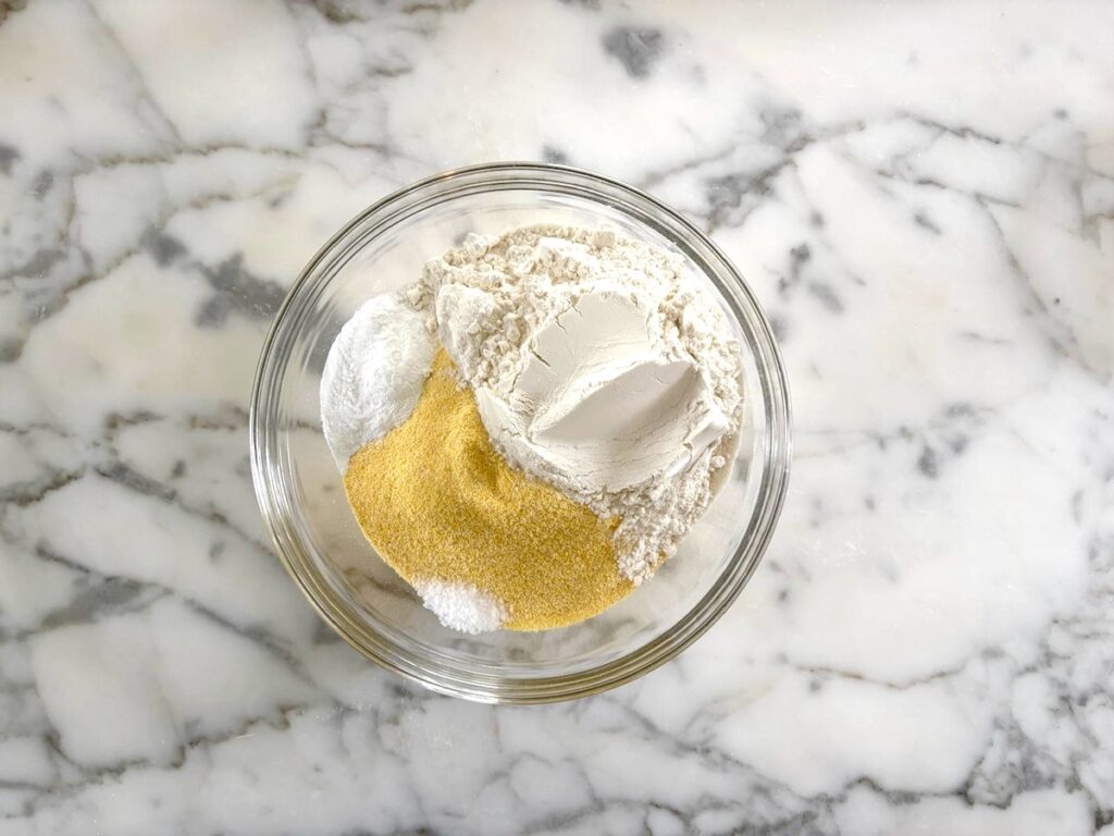 Dry ingredients in a large glass mixing bowl for this Bolo de Fuba, Cornmeal Cake, recipe.